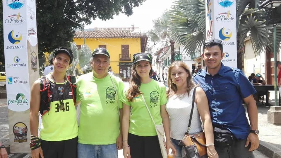 Members of the organizing team in green staff shirts next to a runner in 2016