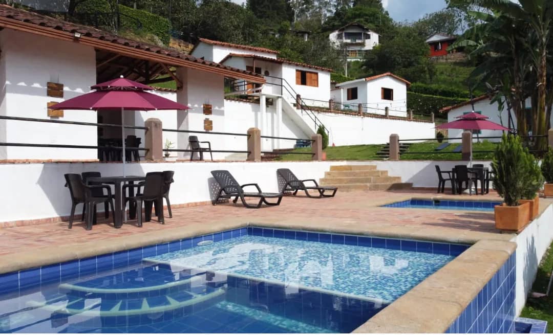 Pool with sun loungers in front of the white cabins at Aires de Encanto