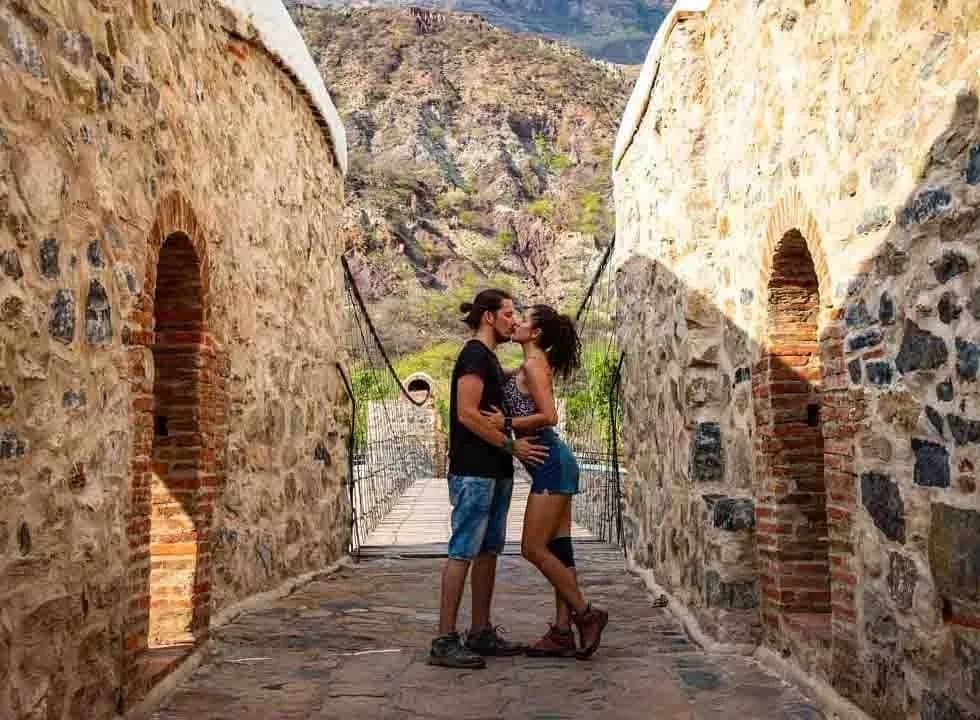 Pareja en el puente de piedra de Jordán, con las montañas del cañón al fondo