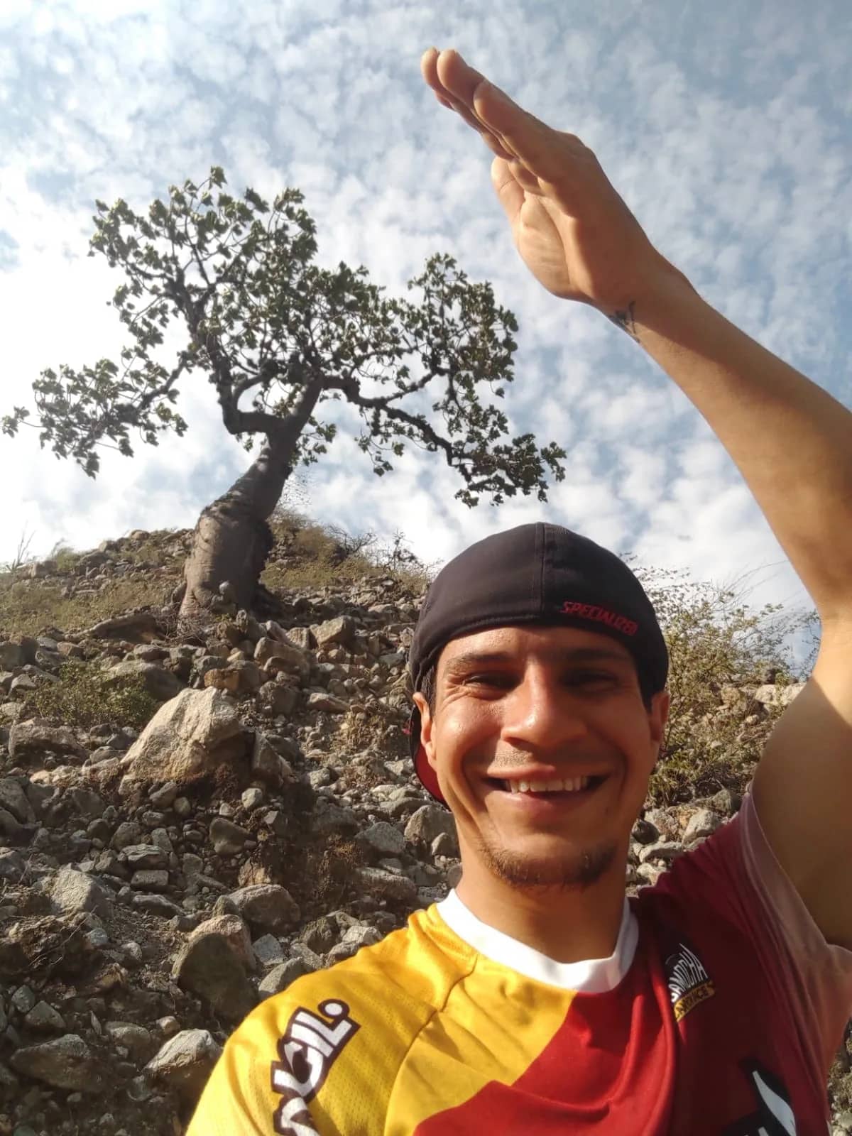 Leonardo Boada Castellanos smiling next to a tree on a rocky canyon slope