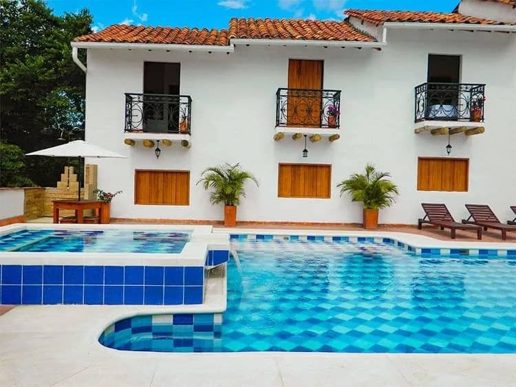 White colonial house with balconies and a tiled pool at Hotel Campestre Victoria