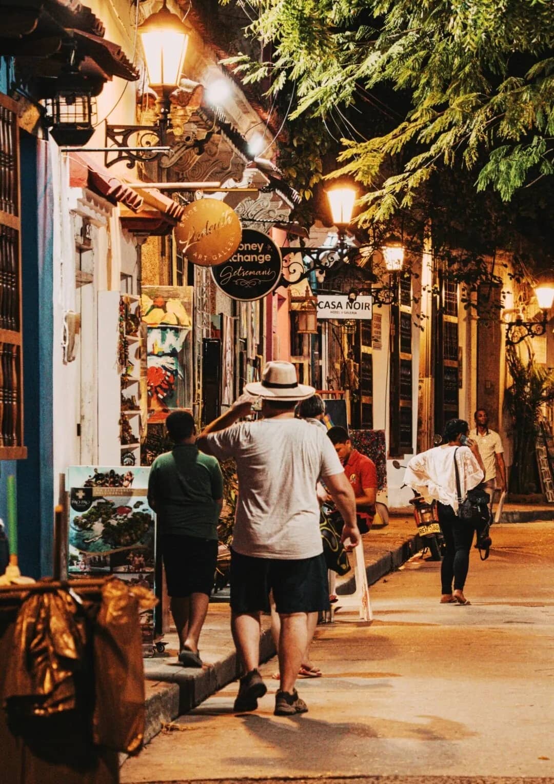 Colonial street in Mompox lit up at dusk, with travelers strolling