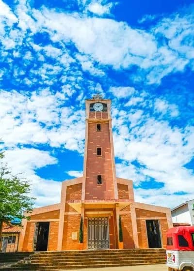 Torre de ladrillo con reloj de la iglesia de Villanueva bajo un cielo con nubes