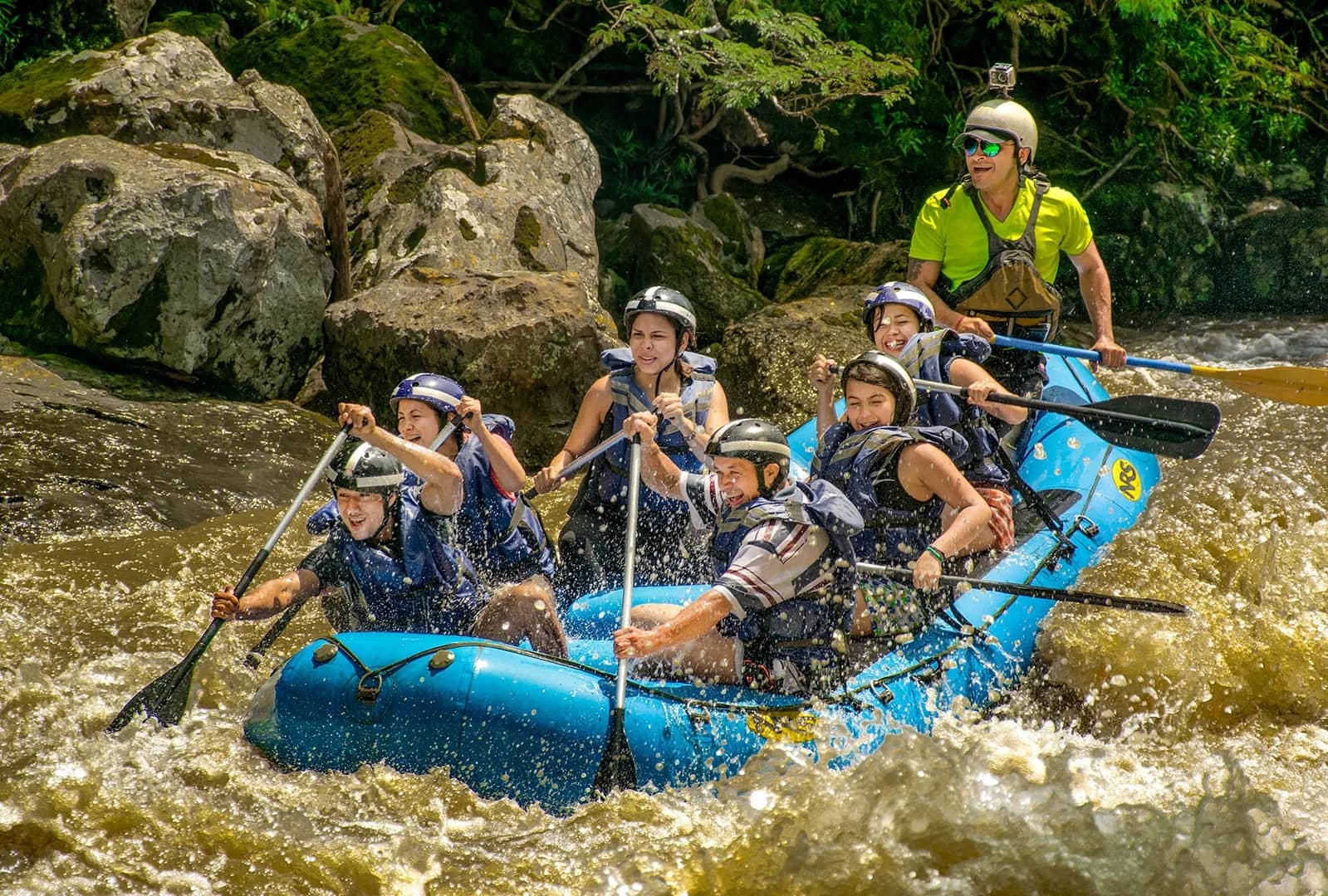 Rafting group in helmets and life jackets running a whitewater rapid