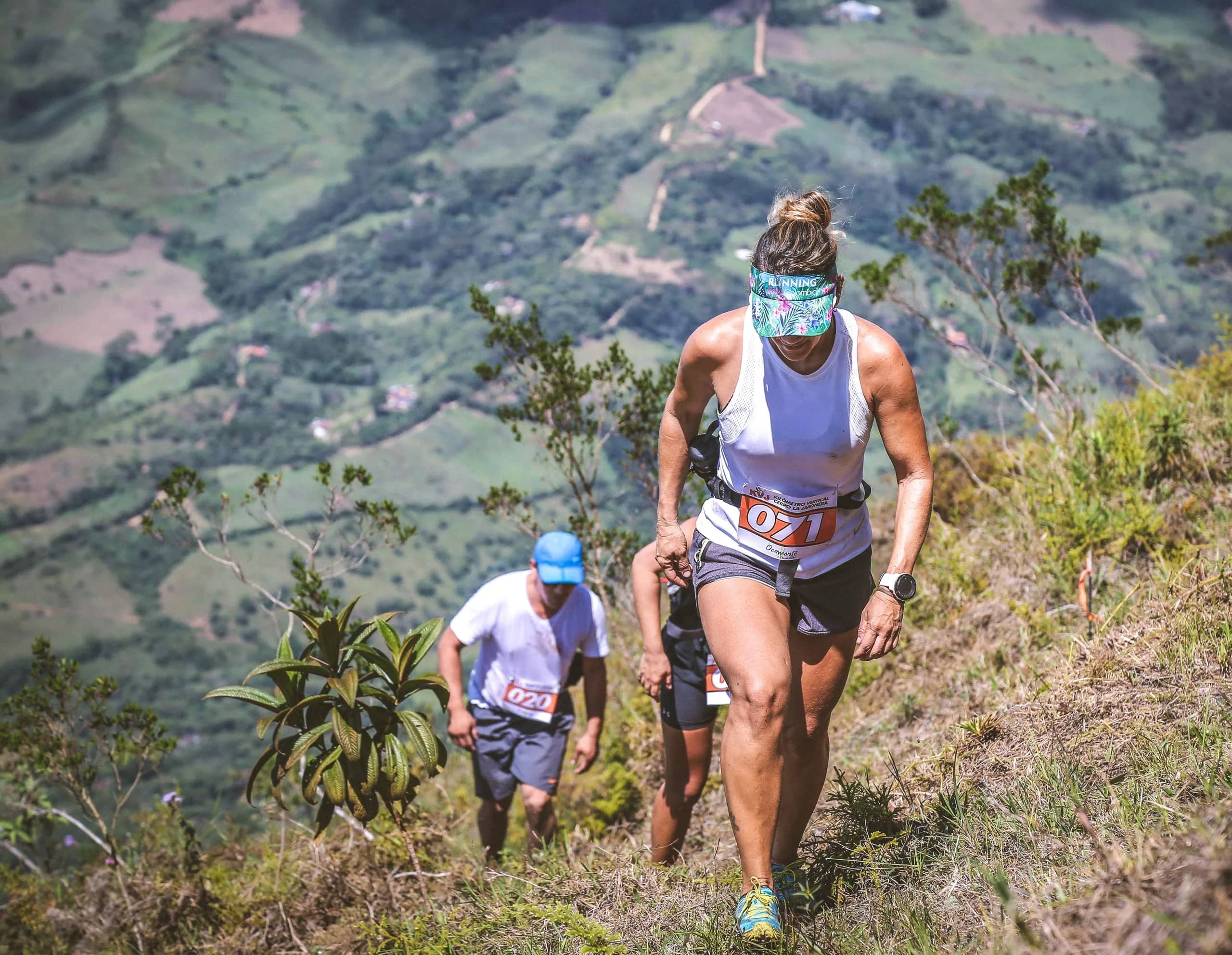 Runner climbing a very steep slope of Cerro La Jabonera, followed by other runners, with the valley below