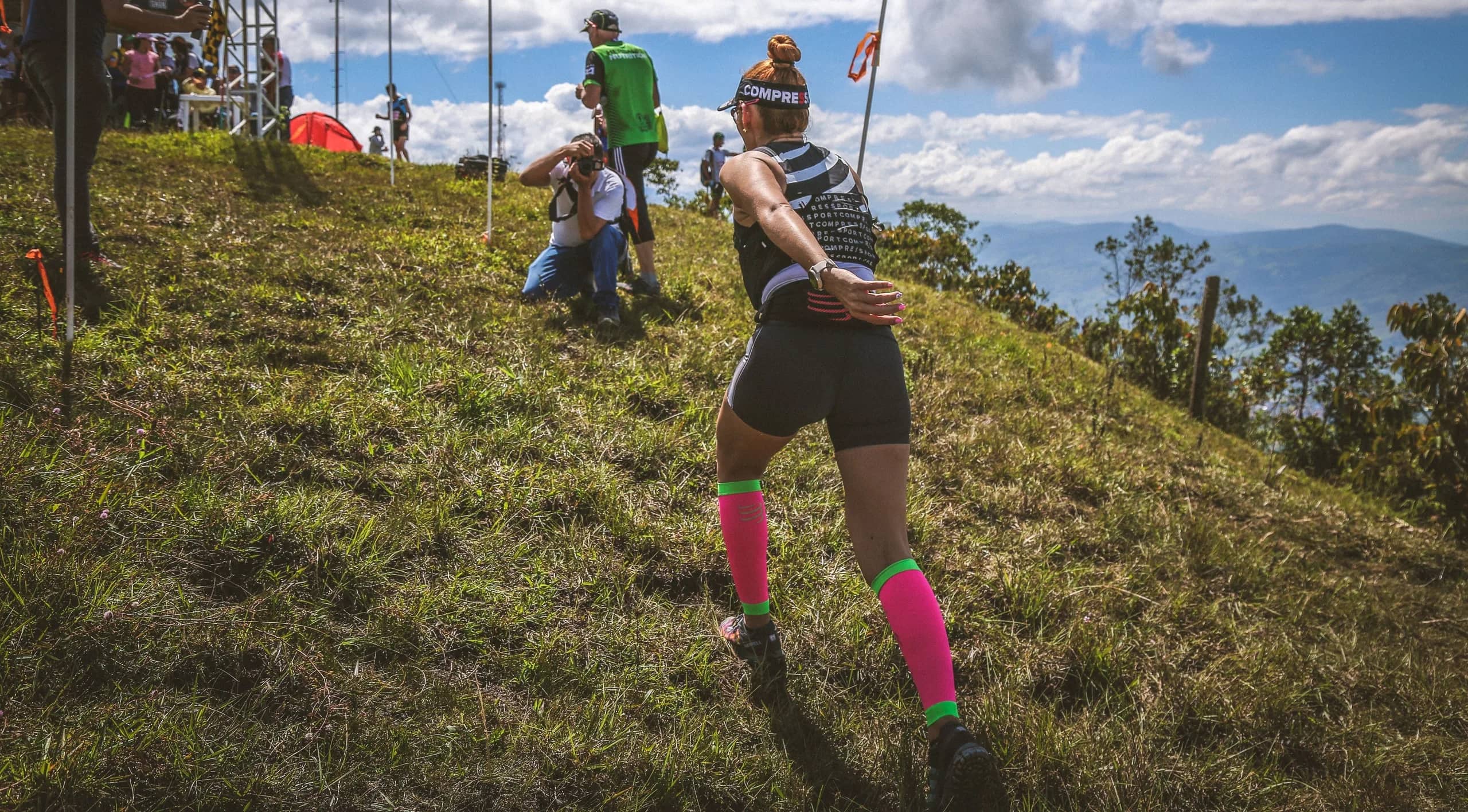 Runner reaching the summit of Cerro La Jabonera, among flags and spectators, under a blue sky