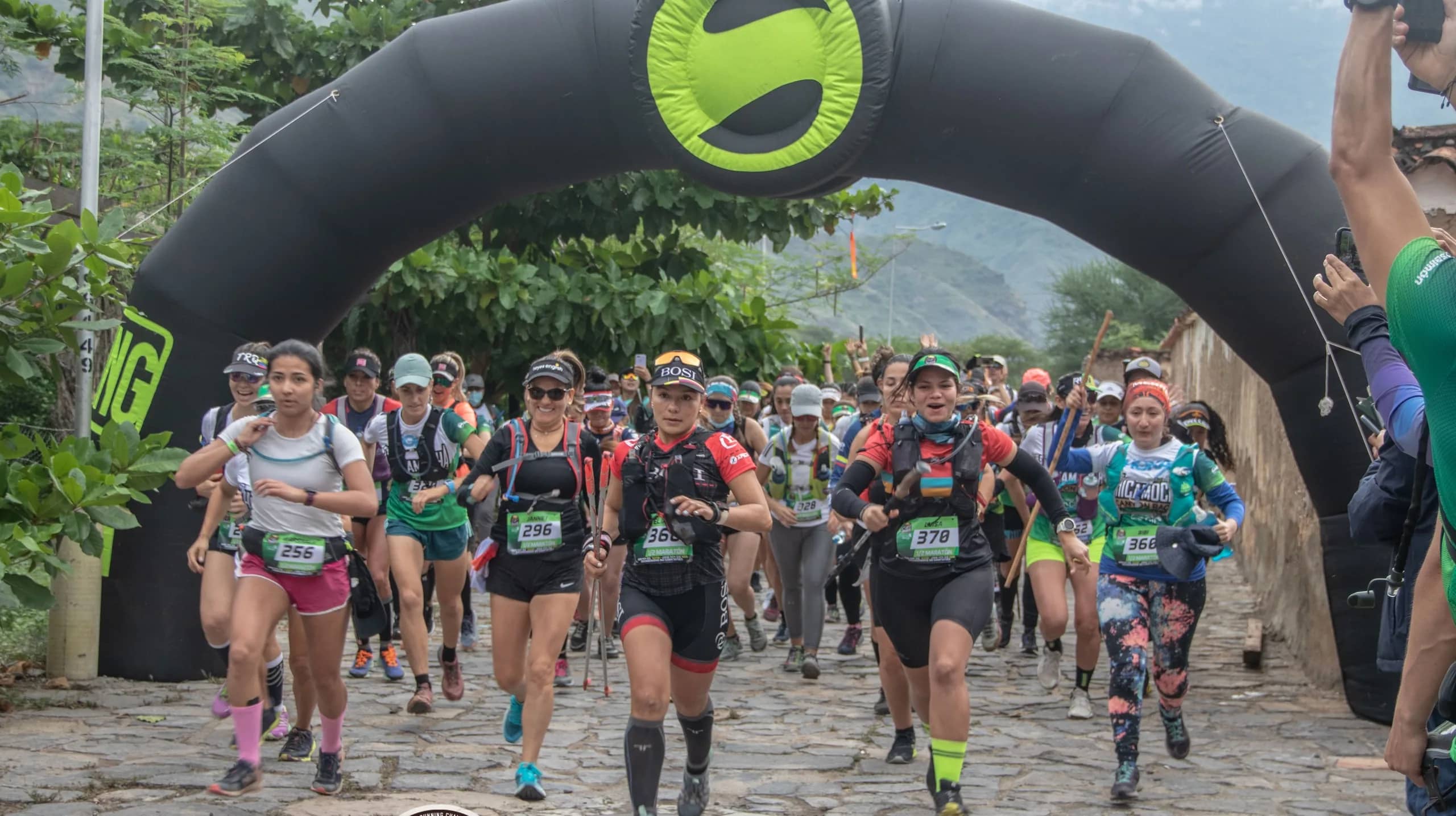 Runners setting off on a cobbled street under an inflatable arch