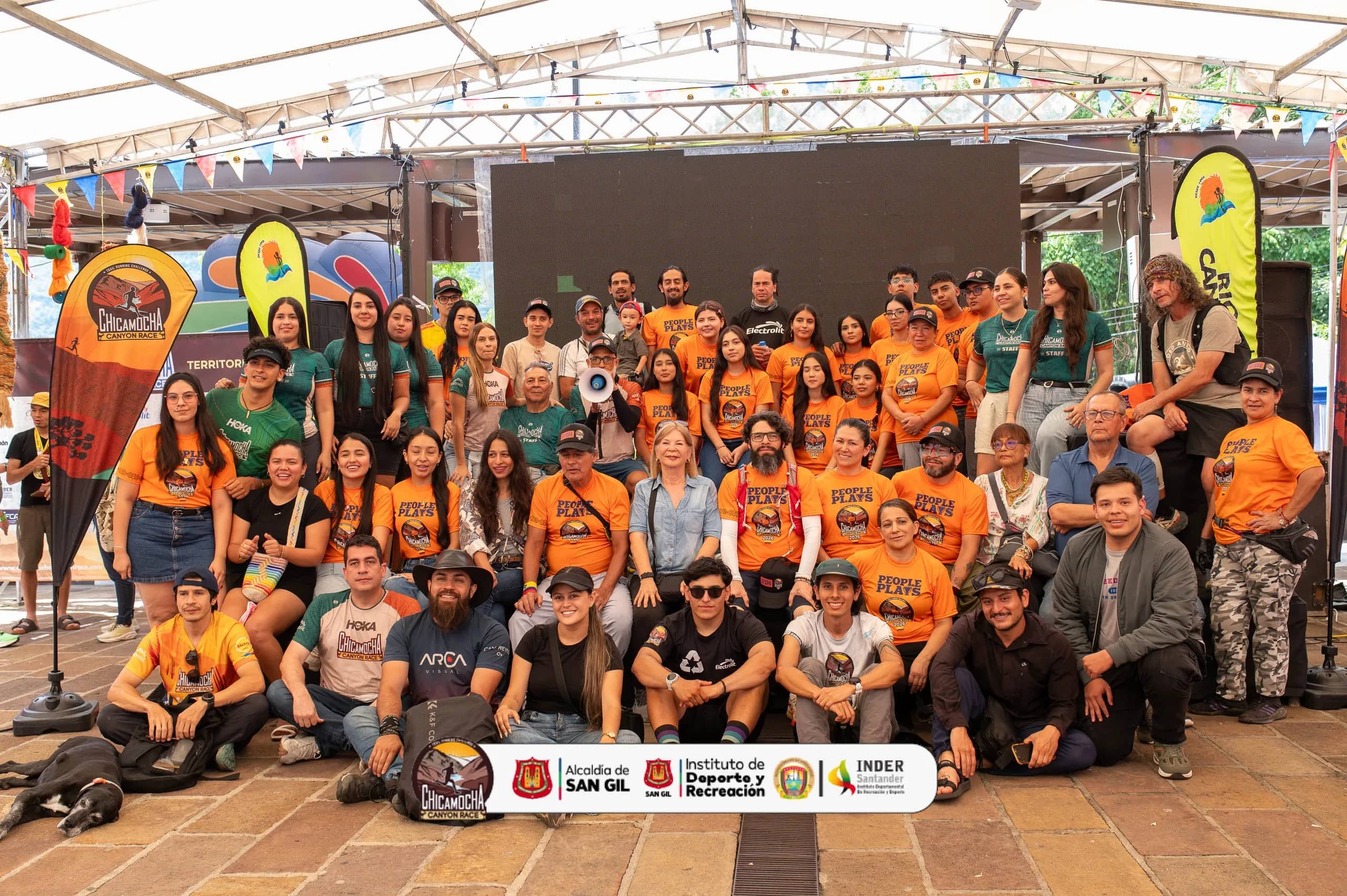 Staff and volunteers in orange shirts pose in the organizers’ tent